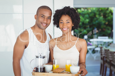 Happy couple holding breakfast tray in the kitchen