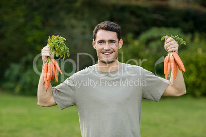 Portrait of young man holding bunch of carrots