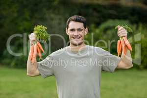 Portrait of young man holding bunch of carrots