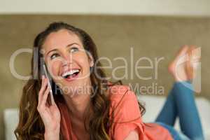 Young woman in bed talking on mobile phone