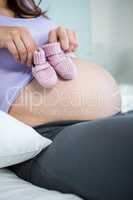 Pregnant woman holding baby shoes over bump