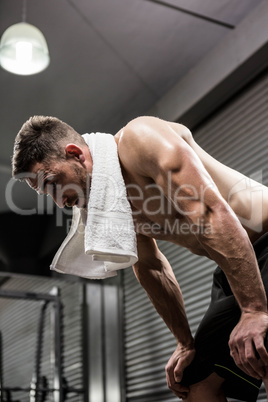 Tired shirtless man with towel around neck