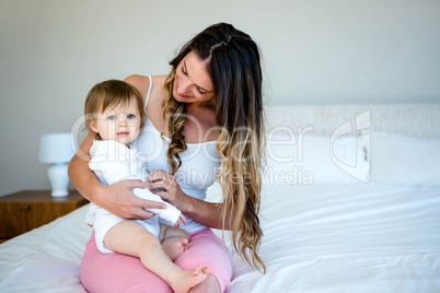 brunette woman holding a baby on a bed