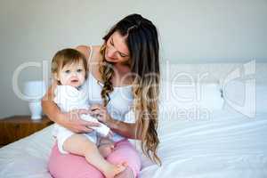 brunette woman holding a baby on a bed