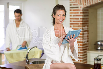 Beautiful woman in bathrobe using digital tablet