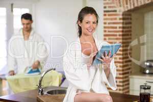 Beautiful woman in bathrobe using digital tablet