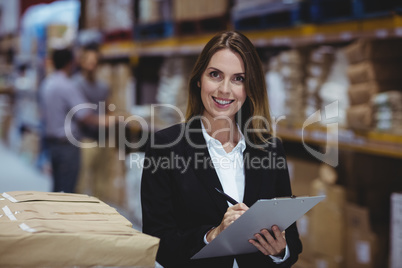 Warehouse manager writing on clipboard