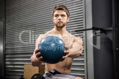 Shirtless man training with medicine ball