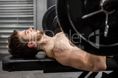 Shirtless man lifting heavy barbell on bench Shirtless man lifting heavy barbell on bench
