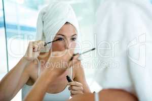 woman applying mascara in the mirror