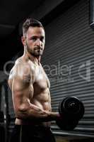 Shirtless man lifting heavy dumbbell