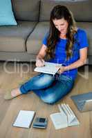 smiling woman sitting on the floor writing
