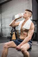 Shirtless man on bench drinking protein shake