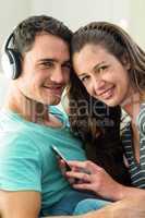 Young couple listening to music on mobile phone