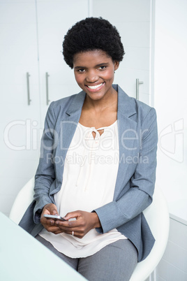 Pregnant businesswoman texting