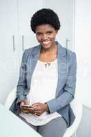 Pregnant businesswoman texting