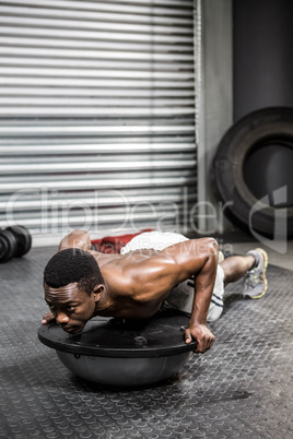 Muscular man doing push up on bosu ball