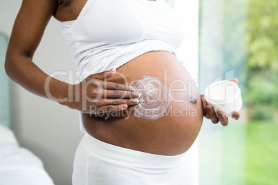 Pregnant woman applying cream on her belly