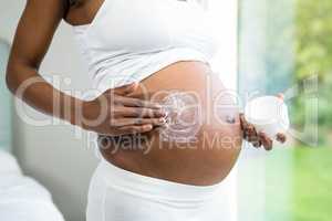 Pregnant woman applying cream on her belly