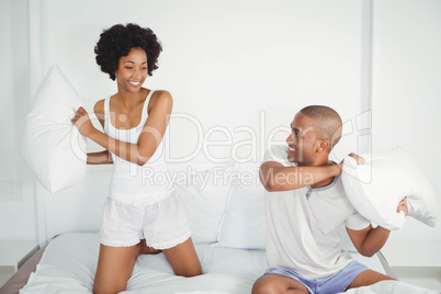 Happy couple having a pillow fight