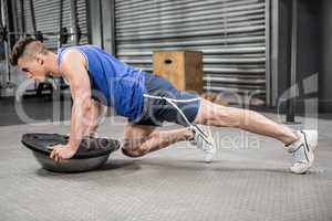 Muscular man doing push up on bosu ball