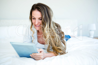 woman lying on her bed browsing on her tablet