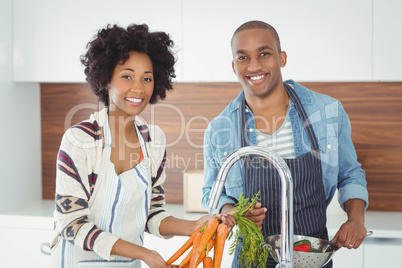 Happy couple washing vegetables
