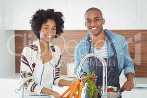 Happy couple washing vegetables