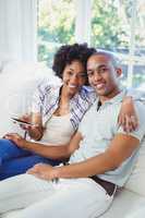 Happy couple using smartphone on the sofa