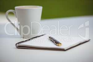 Overhead of notebook with pen and coffee