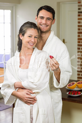 Man feeding strawberry to woman