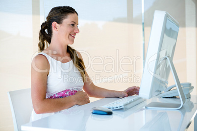 smiling pregnant business woman on her computer