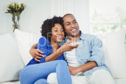 happy couple watching television on the sofa