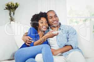 happy couple watching television on the sofa