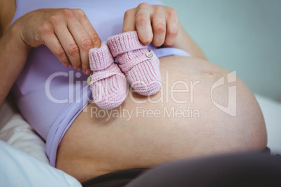 Pregnant woman holding baby shoes over bump