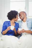 Happy couple holding cups on the sofa