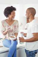 Happy couple eating breakfast and using smartphone