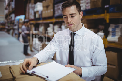 Warehouse manager looking at clipboard