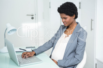 Pregnant businesswoman using laptop