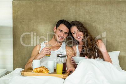 Young couple having breakfast on bed