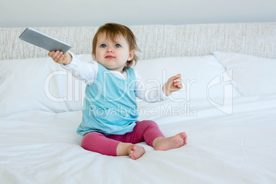 Blue eyed baby holding out a mobile phone