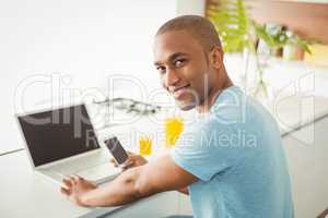 Smiling man using laptop and smartphone