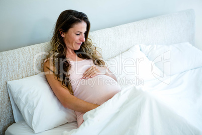 pregnant woman in bed holding her bump