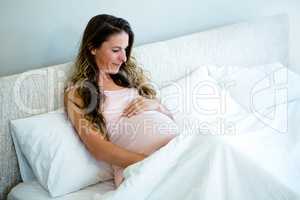 pregnant woman in bed holding her bump