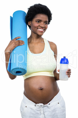 Pregnant woman holding water bottle and mat