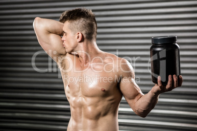 Shirtless man kissing biceps and holding can