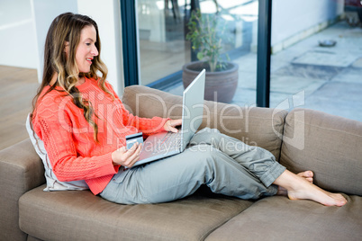 smiling woman on her laptop with her credit card