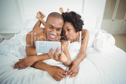 Smiling couple taking selfie on the bed