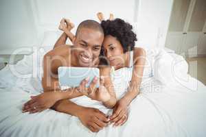 Smiling couple taking selfie on the bed