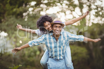 Handsome man giving piggy back to his girlfriend